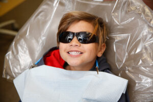 Smiling boy wearing sunglasses in a dentist chair