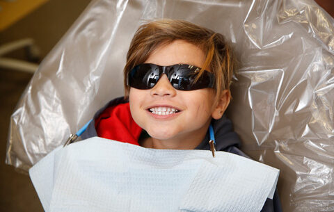 Smiling boy wearing sunglasses in a dentist chair