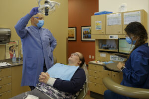 Dentist and dental assistant talking to a patient, who is lying down in the dental chair
